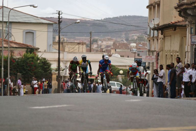 Riders climb a street in Asmara, watched by spectators