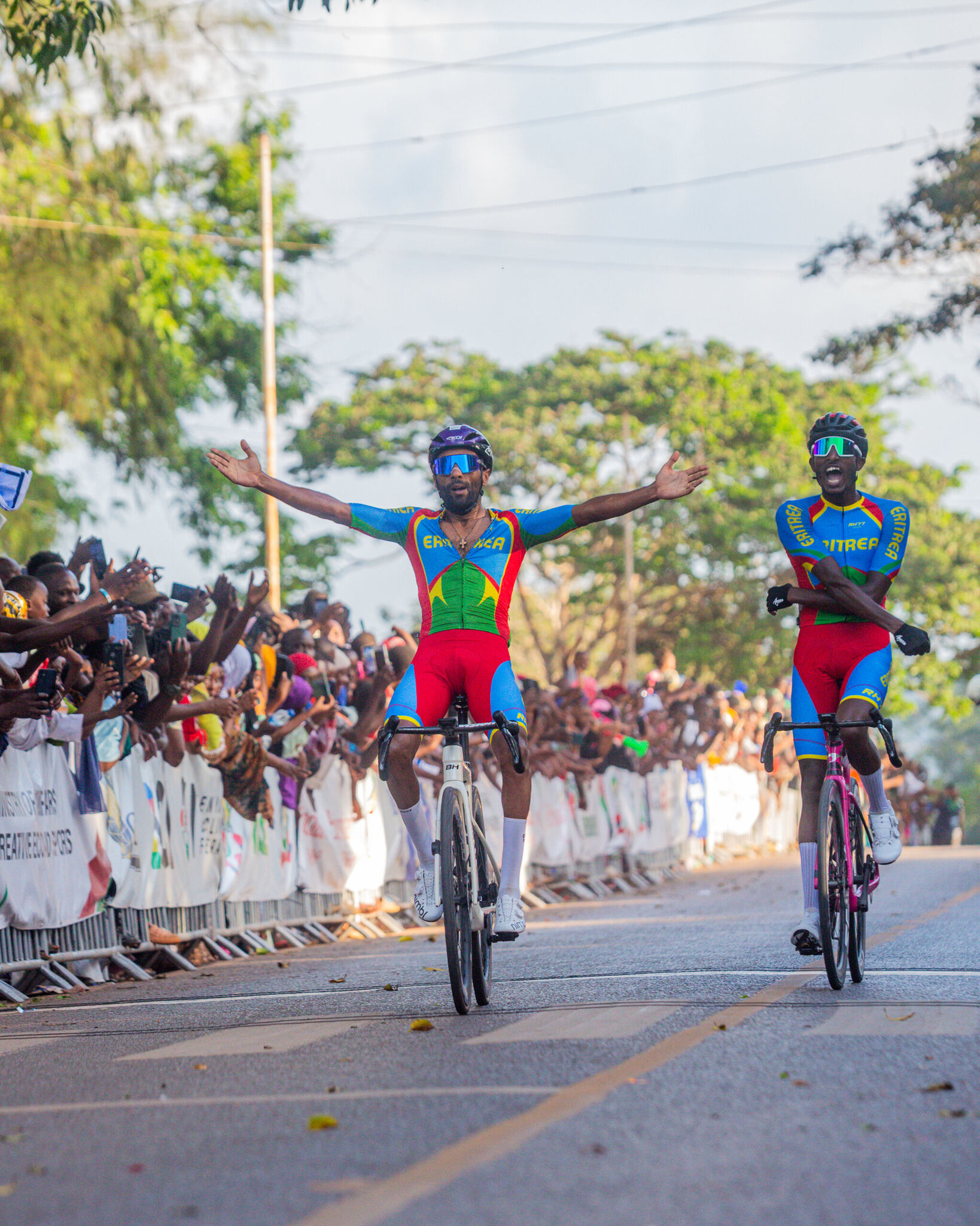 Two Eritrean riders raise their arms as they cross the finish line