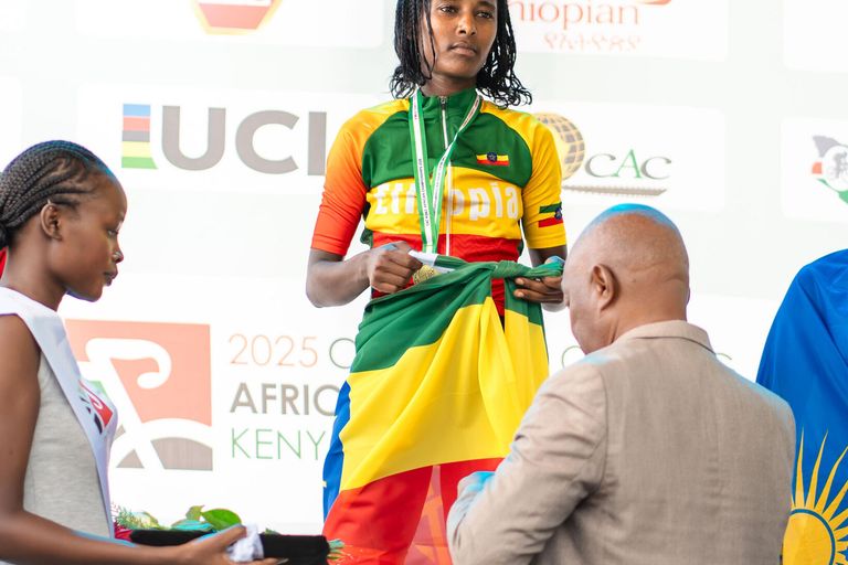 A rider wrapped in the Ethiopian flag receives her medal on the podium