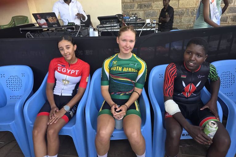 Three riders sitting side by side on blue chairs, in the jerseys of Egypt, South Africa and Kenya
