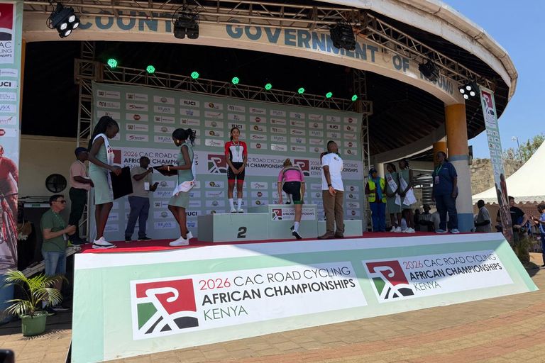 The winner steps up onto the top step of the 2026 African Road Championships podium in Kisumu, next to the runner-up already in place