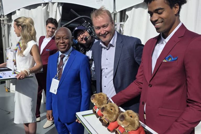Le président de la CAC à côté d'un hôte qui tient un plateau de mascottes en peluche