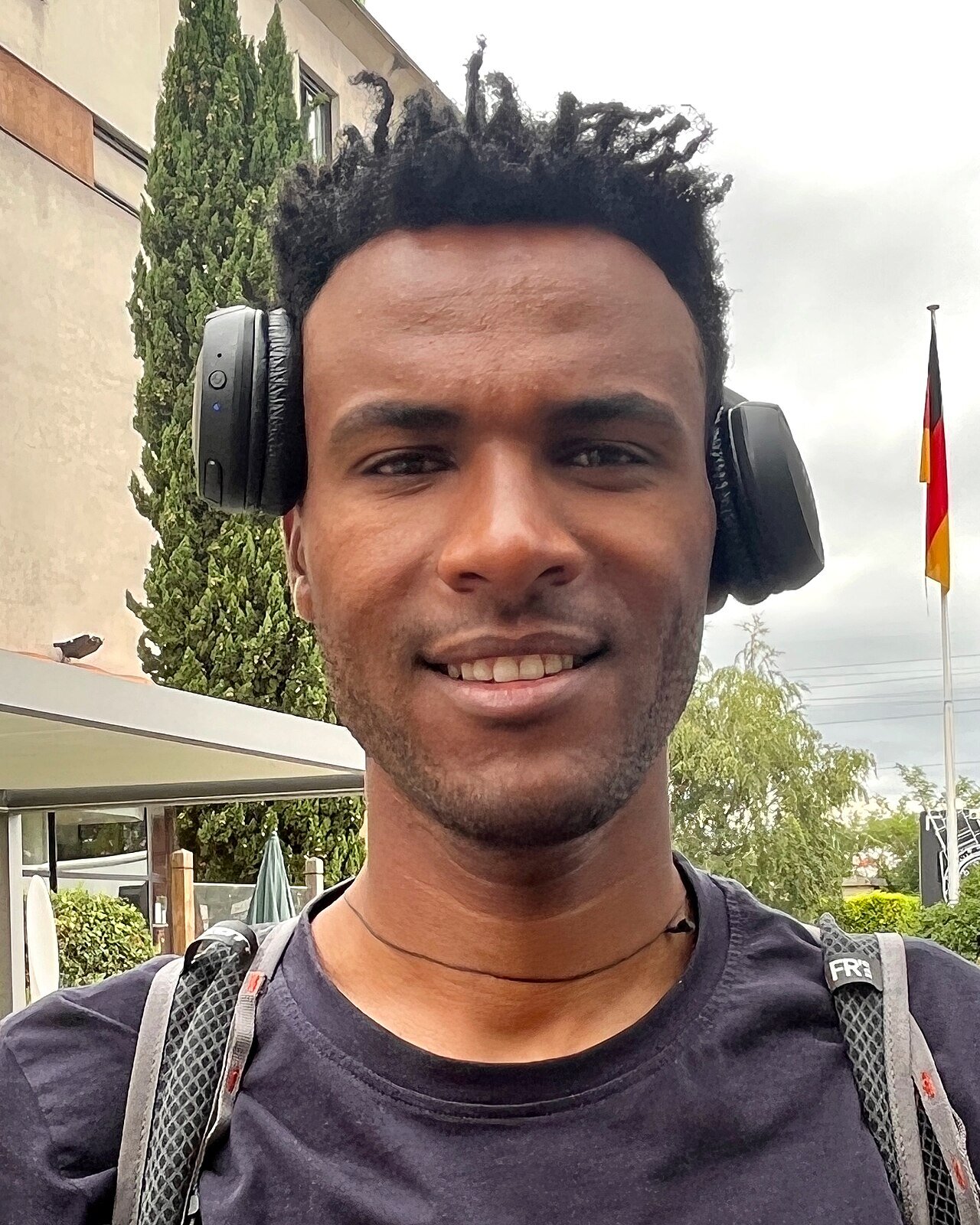 Portrait de Negasi Abreha, souriant, un casque audio autour du cou